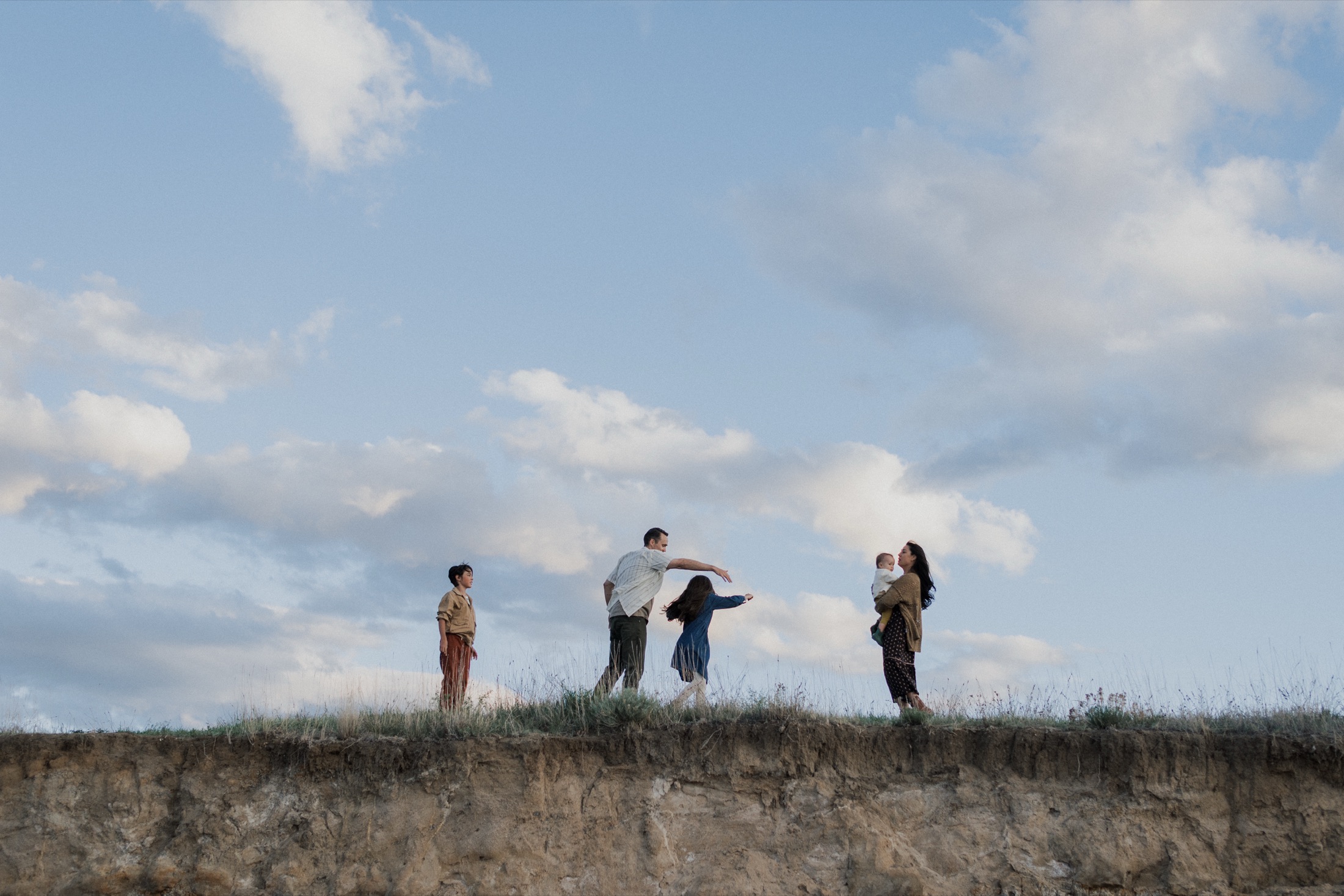 A family playing together on a bluff at golden hour